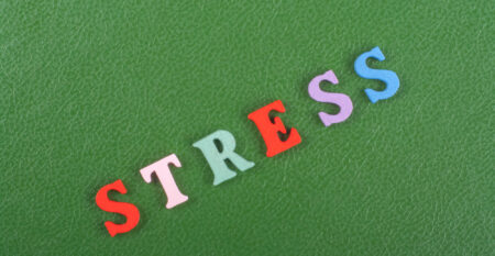 STRESS word on green background composed from colorful abc alphabet block wooden letters, copy space for ad text. Learning english concept.